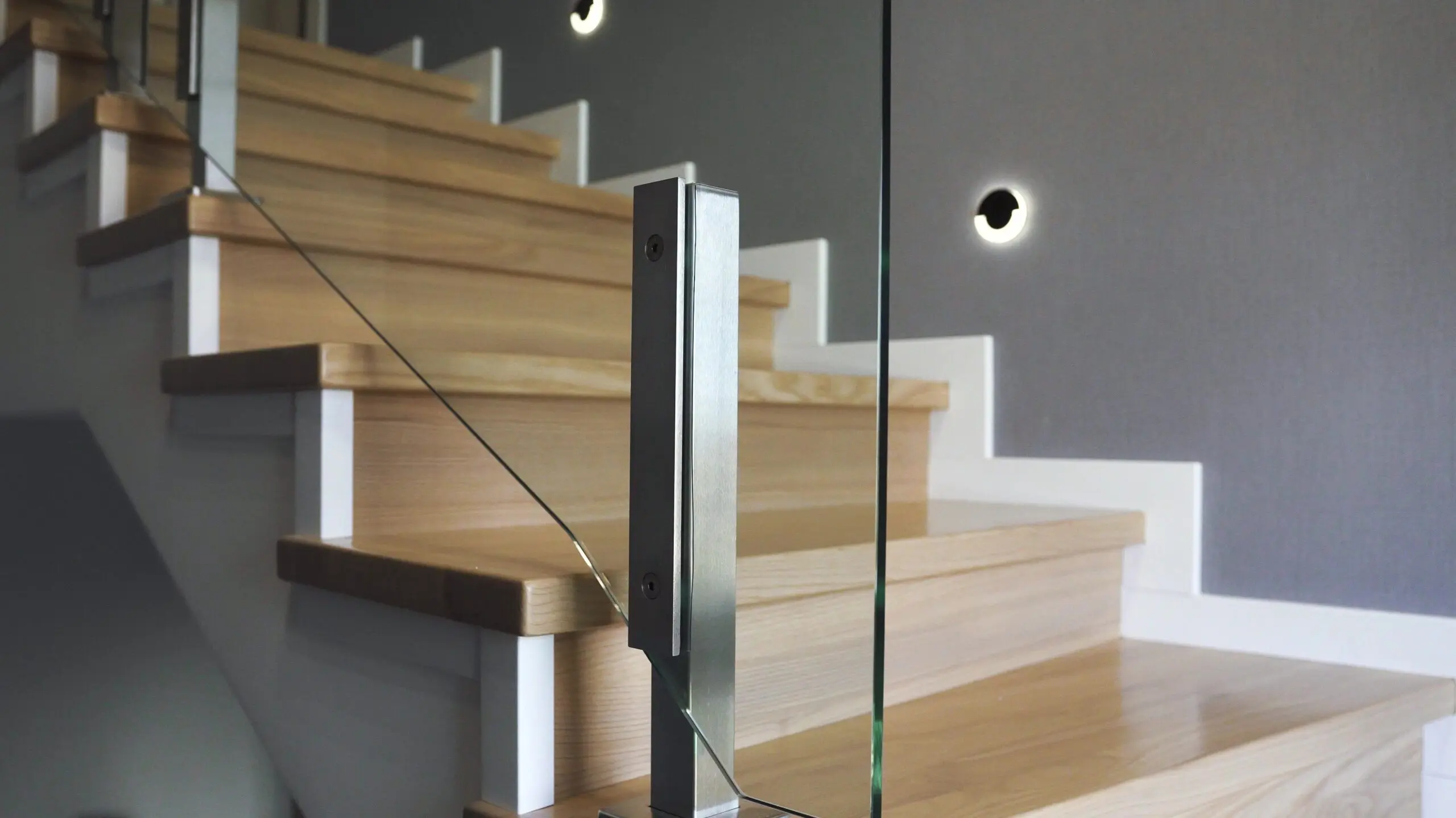 Close view of a set of wood indoor stairs with a glass railing