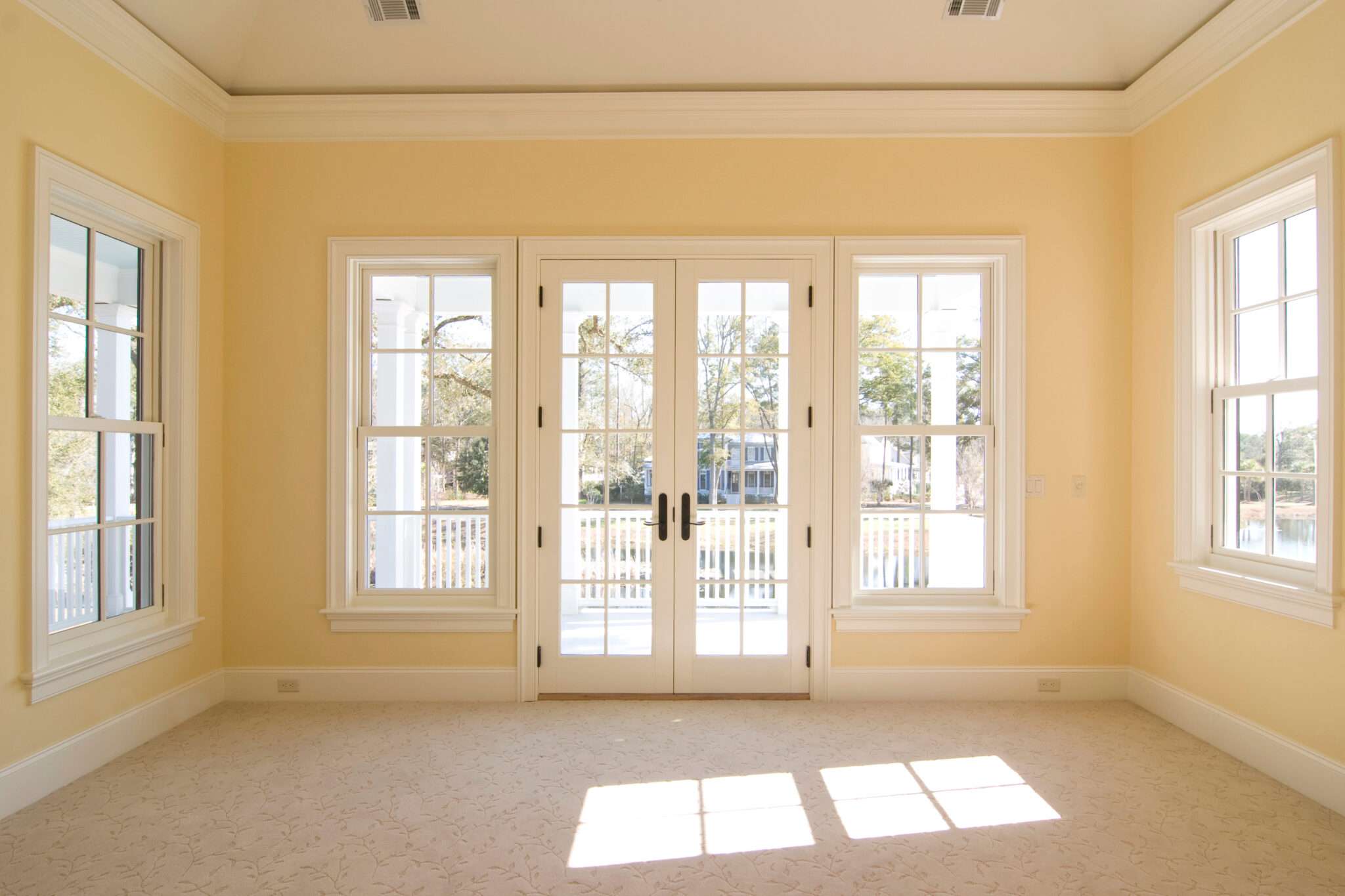 Patio doors and windows in empty room with yellow walls