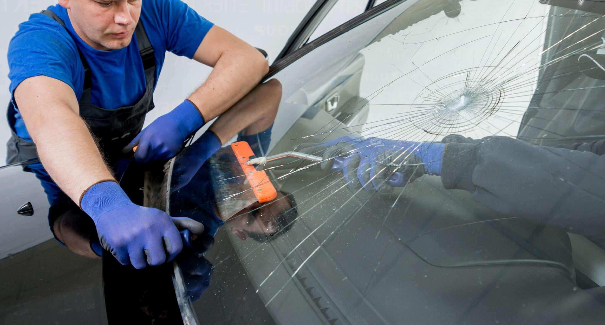 Man in blue replacing broken windshield