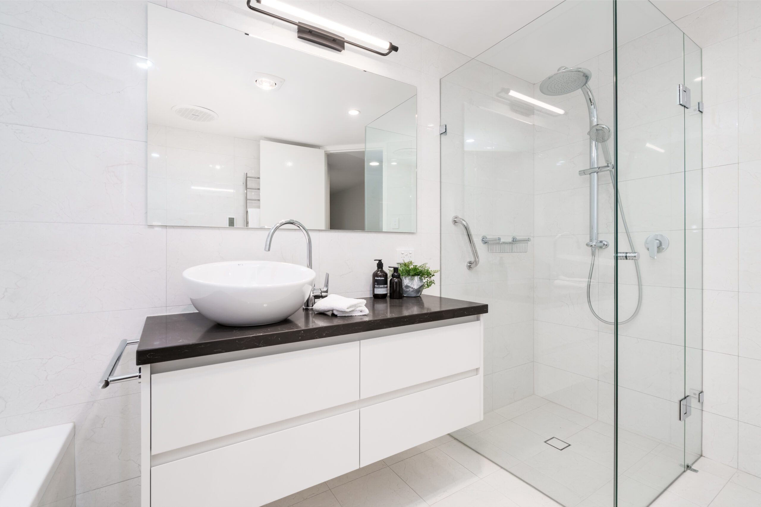 Glass shower enclosure in modern white bathroom