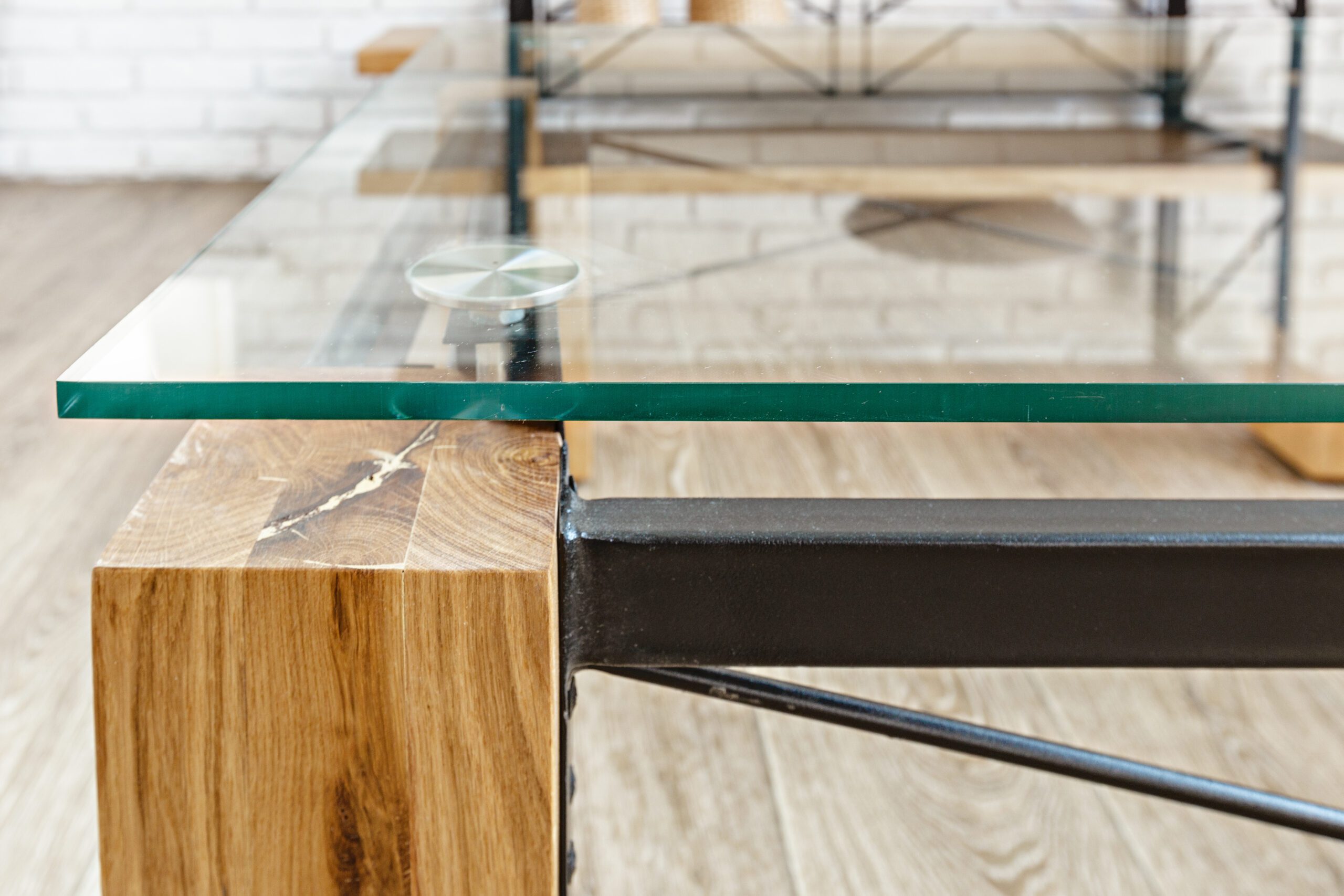 Glass tabletop close up with wood legs and metal brackets