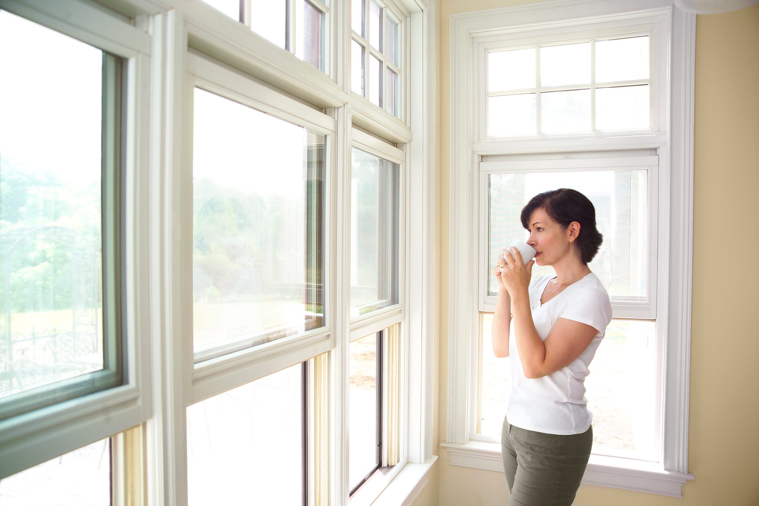 Woman looking out windows drinking coffee