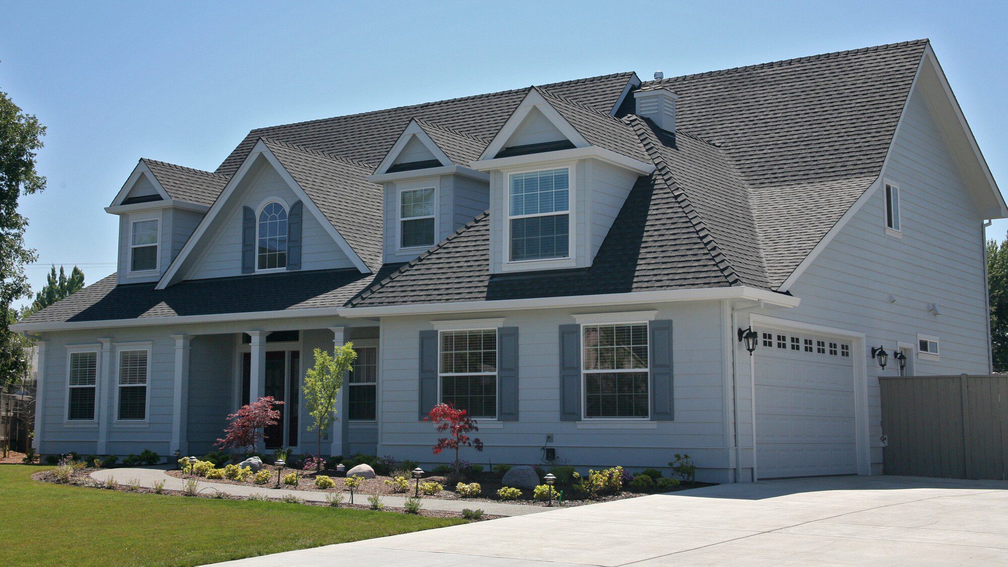 Exterior view of home with beautiful white siding, asphalt roofing, and Infinity glass windows by GoGlass