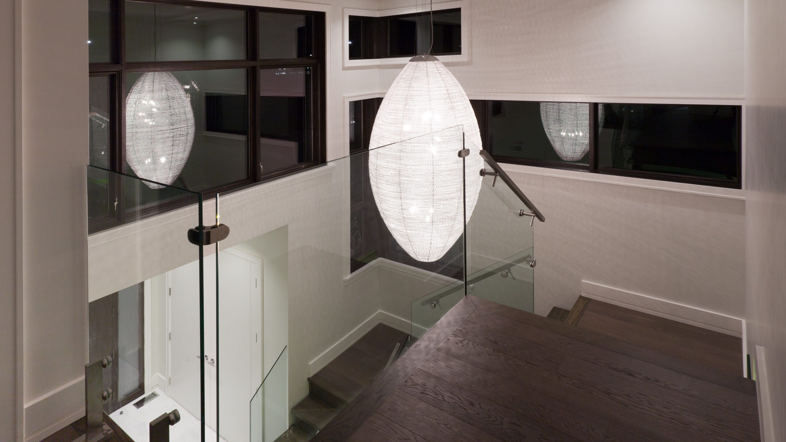 Nighttime view of an interior residential stair with glass railings