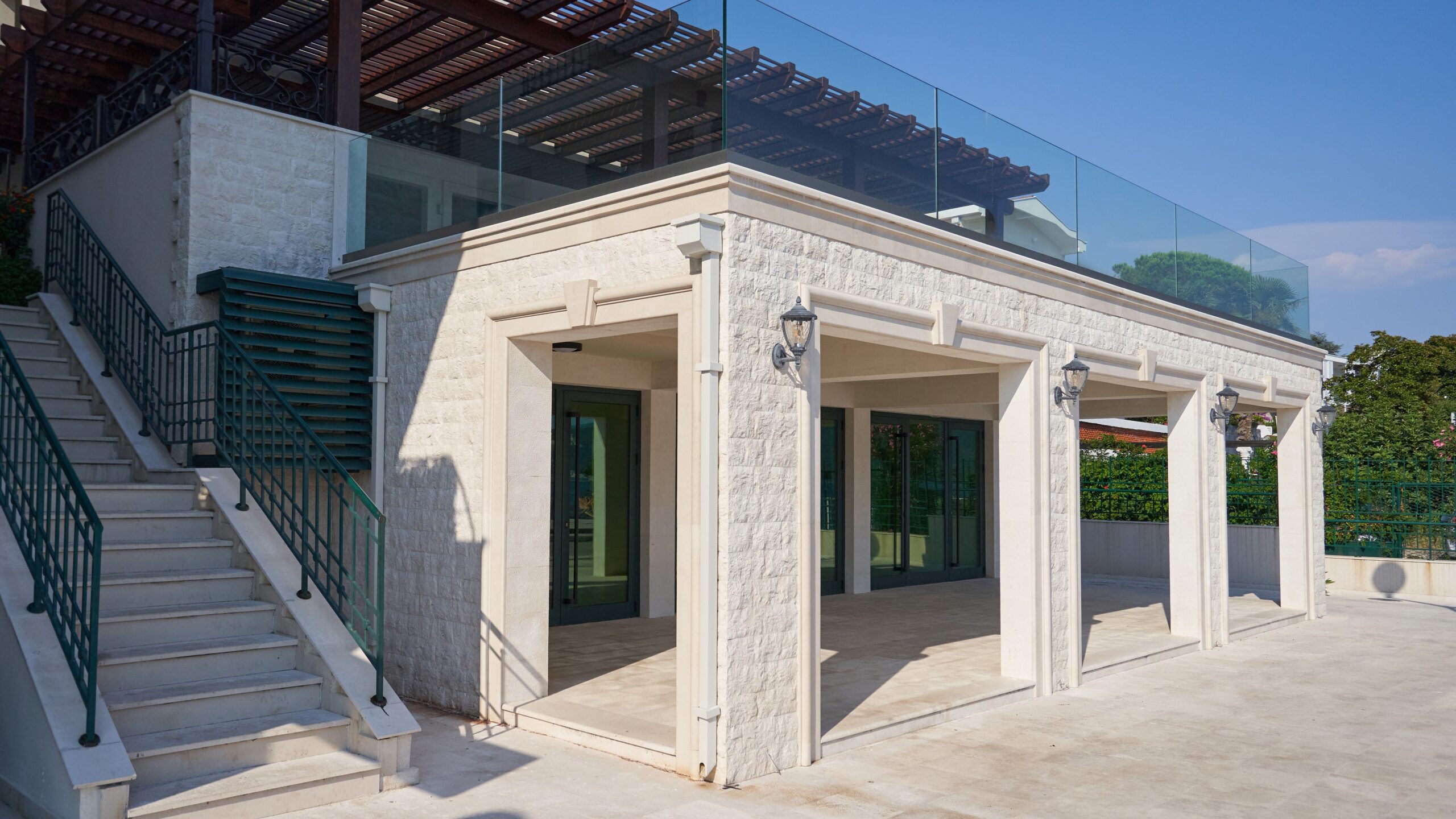 Exterior view of a large stone house a glass railing on a second-floor terrace