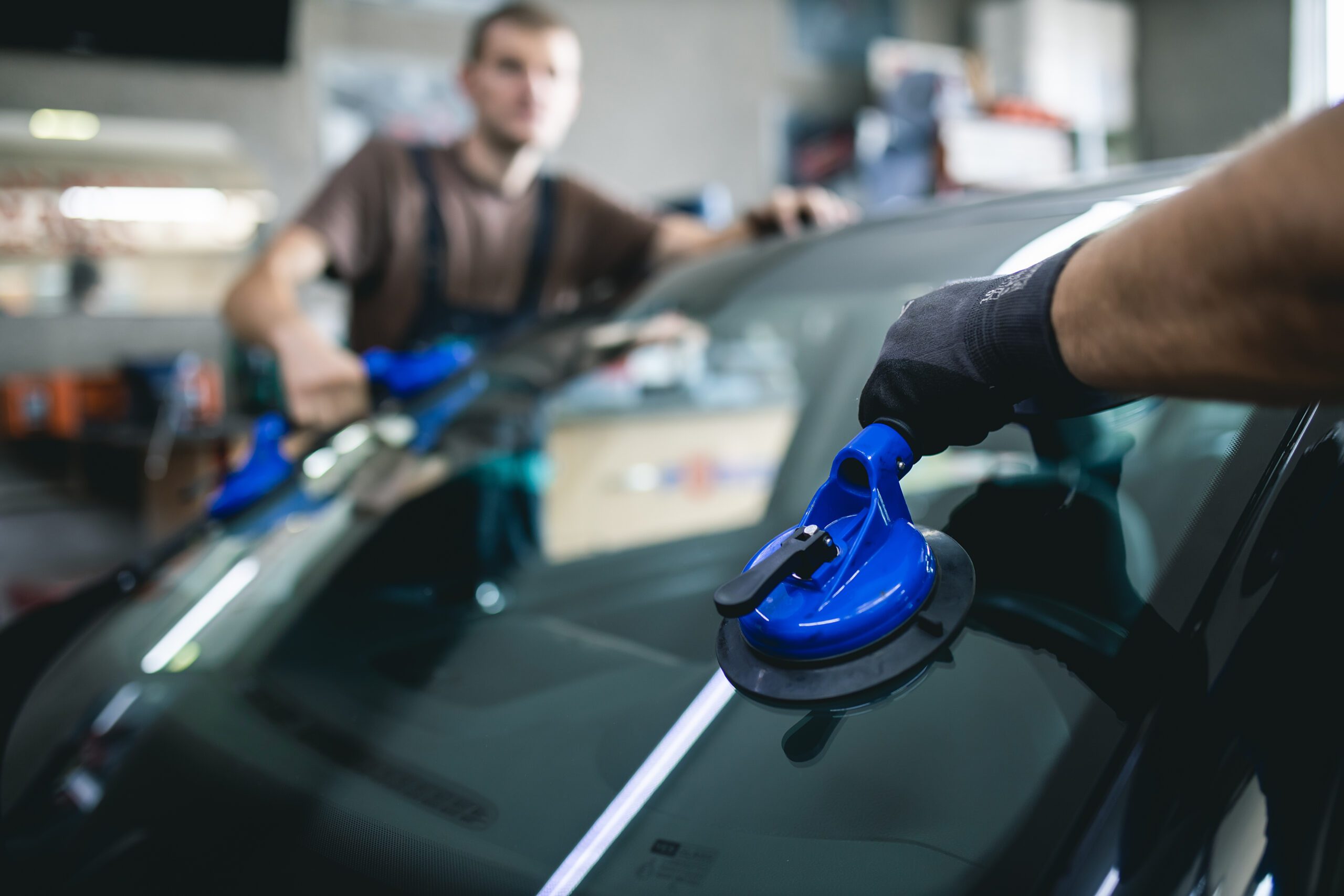 A windshield is being placed onto the car by men